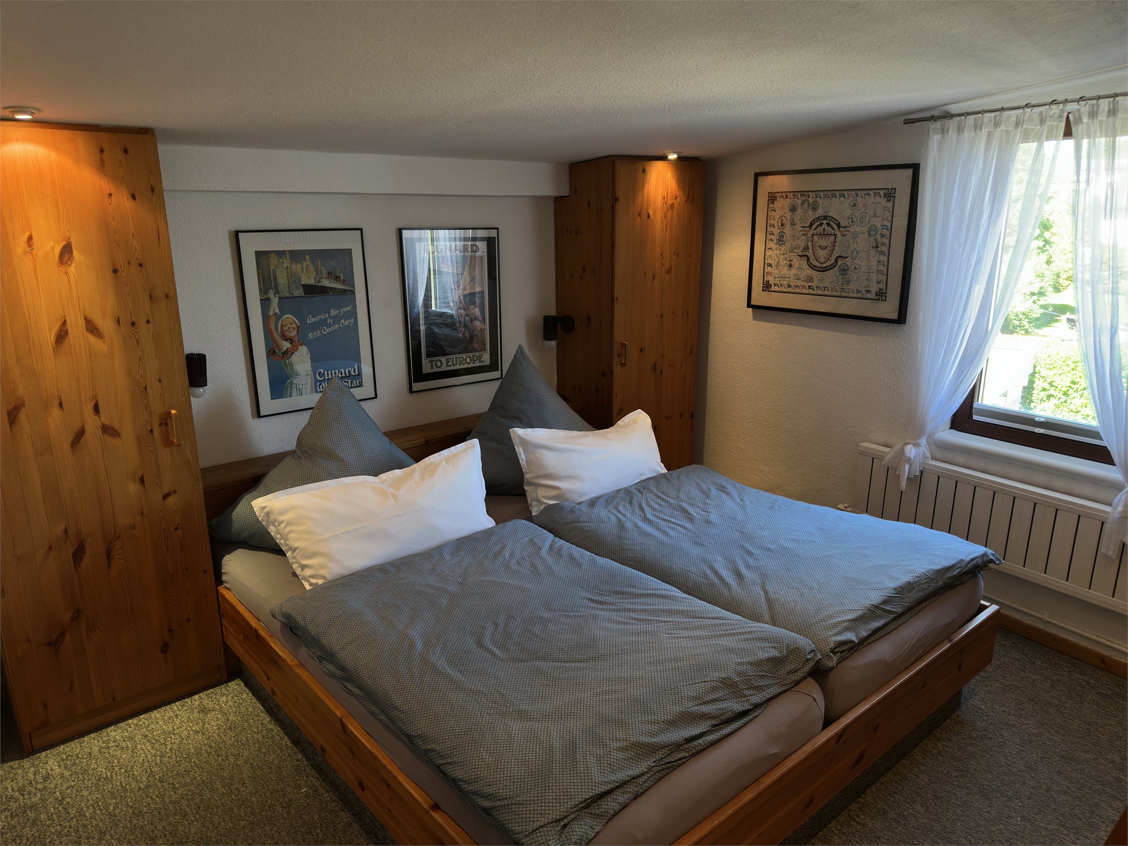 Doppelbett mit Holzschränken und heller Fensterseite