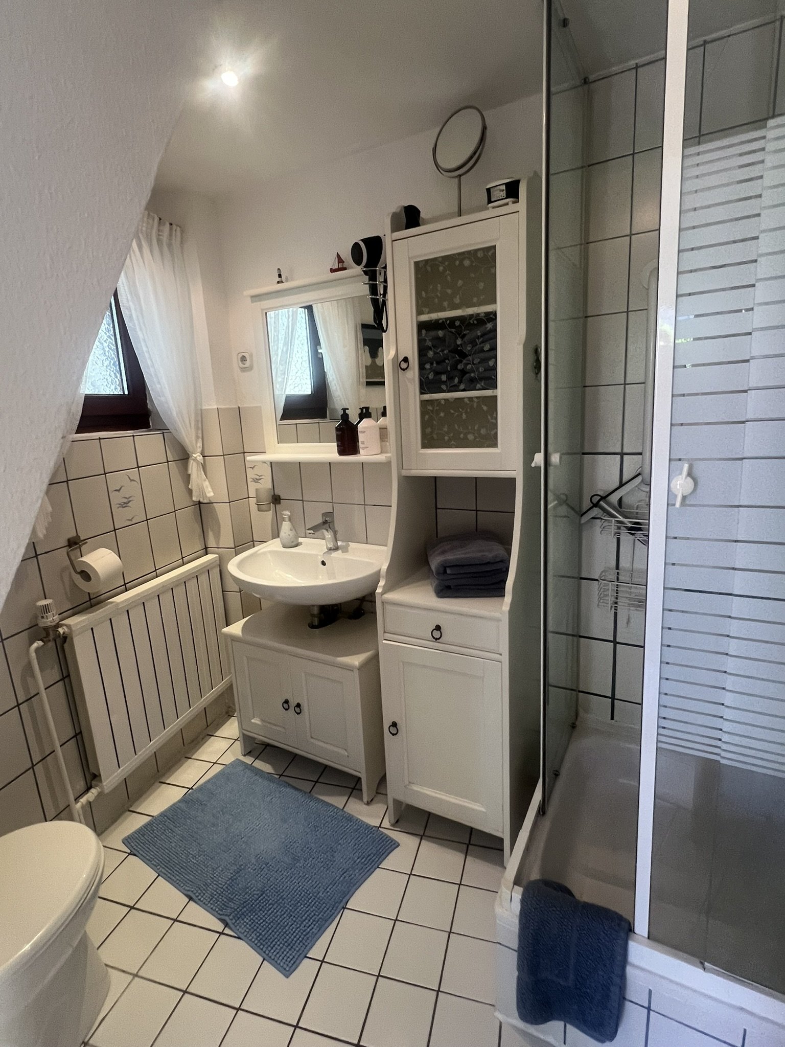 Helles Bad mit Dusche, Waschbecken und Handtüchern