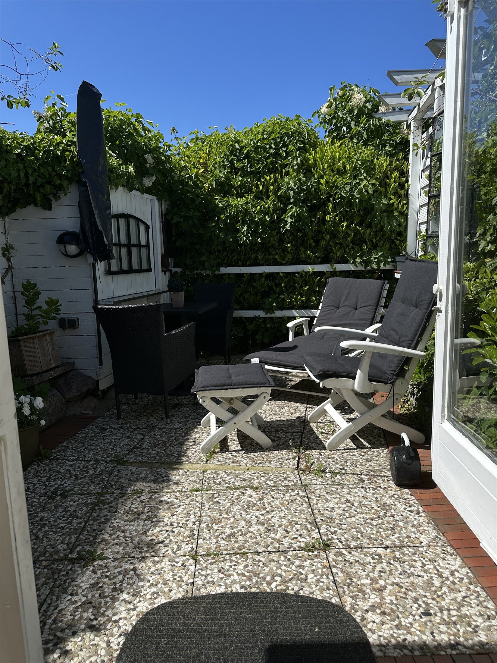Terrasse mit Liegestühlen, Sitzgruppe und grüner Bepflanzung