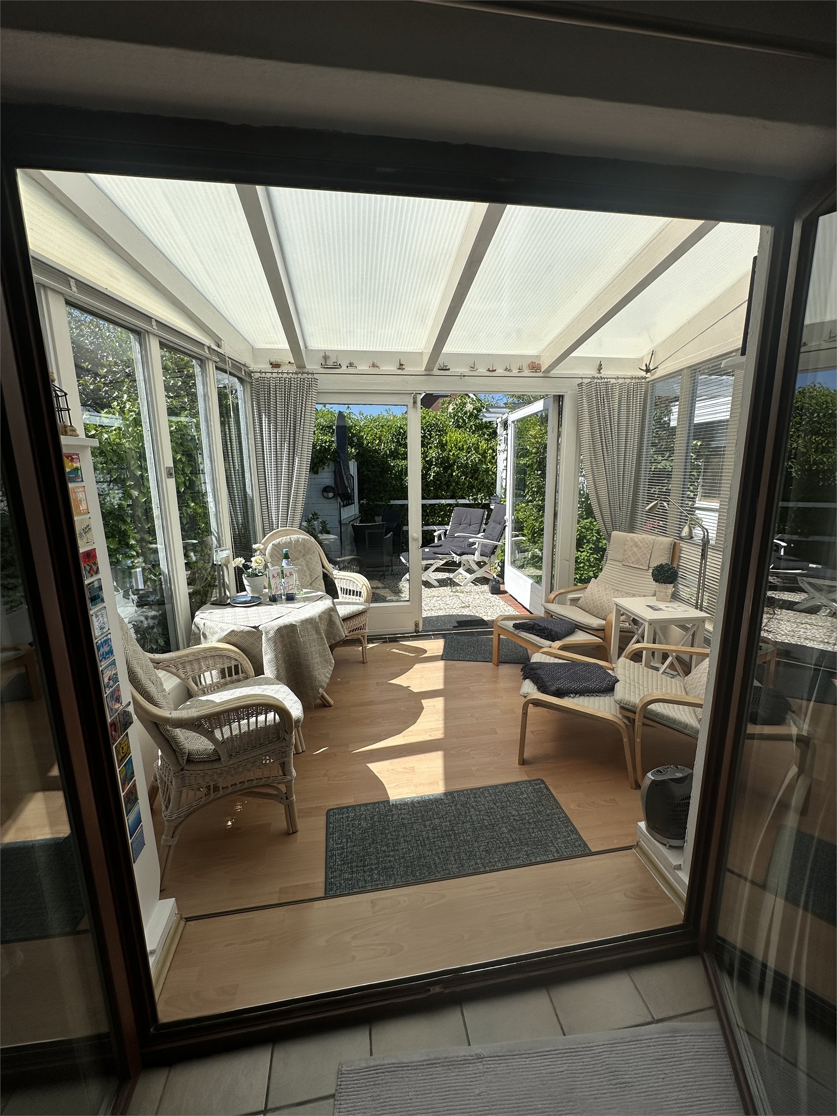 Blick vom Haus in den hellen Wintergarten und zur Terrasse