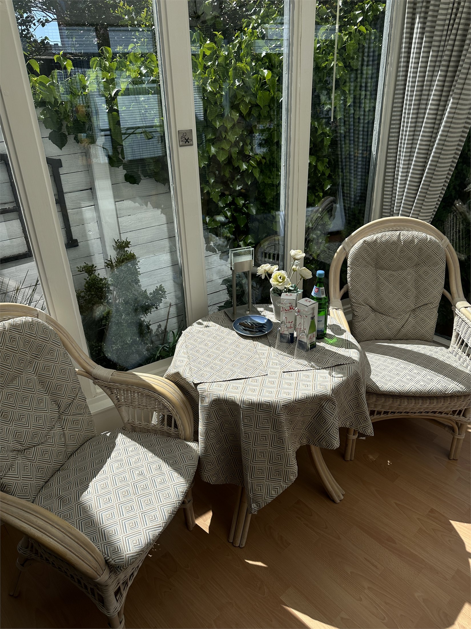Runder Tisch mit Korbstühlen im sonnigen Wintergarten